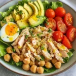 Salade protéinée au poulet, avocat et pois chiches servie dans un bol blanc, garnie de persil frais.