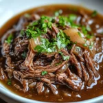 Plat de bœuf effiloché fondant aux oignons servi dans une cocotte en fonte