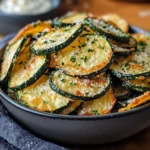 Chips de courgettes dorées et croustillantes sur une plaque de cuisson, prêtes à être dégustées.