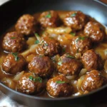 Boulettes de bœuf moelleuses nappées de sauce aux oignons caramélisés dans une poêle