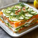 Lasagnes froides de concombre, saumon et sauce citron-aneth servies en assiette élégante.