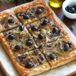 Pissaladière niçoise dorée sortie du four avec oignons fondants, anchois en croisillons et olives noires