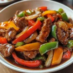 Lanières de bœuf sautées avec poivrons rouges et jaunes et oignons, servies dans un wok fumant