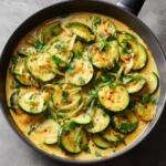 Plat de courgettes sautées au lait de coco et curry dans une poêle avec oignons et herbes fraîches