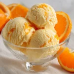 Glace à l’orange maison dans un bol, servie crémeuse avec morceaux d’orange