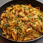 Assiette de Lo Mein au Poulet et à l’Ail garnie de légumes colorés et de nouilles brillantes