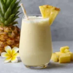 Smoothie Piña Colada servi dans un verre décoré avec tranche d’ananas