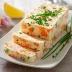 Terrine de surimi fraîchement démoulée, servie en tranches sur une assiette avec citron et herbes fraîches