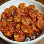 Crevettes nappées de sauce au miel dans une poêle chaude, prêtes à être servies