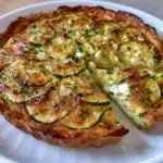 Quiche sans pâte au fromage de chèvre et courgettes servie tiède dans une assiette avec salade verte.