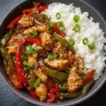 Assiette de sauté de poulet à l’ail grillé avec poivrons colorés et riz jasmin vapeur.